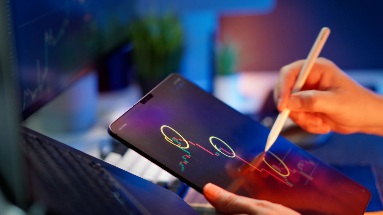 about-us Person analyzing cryptocurrency trends on a tablet with digital pen.
